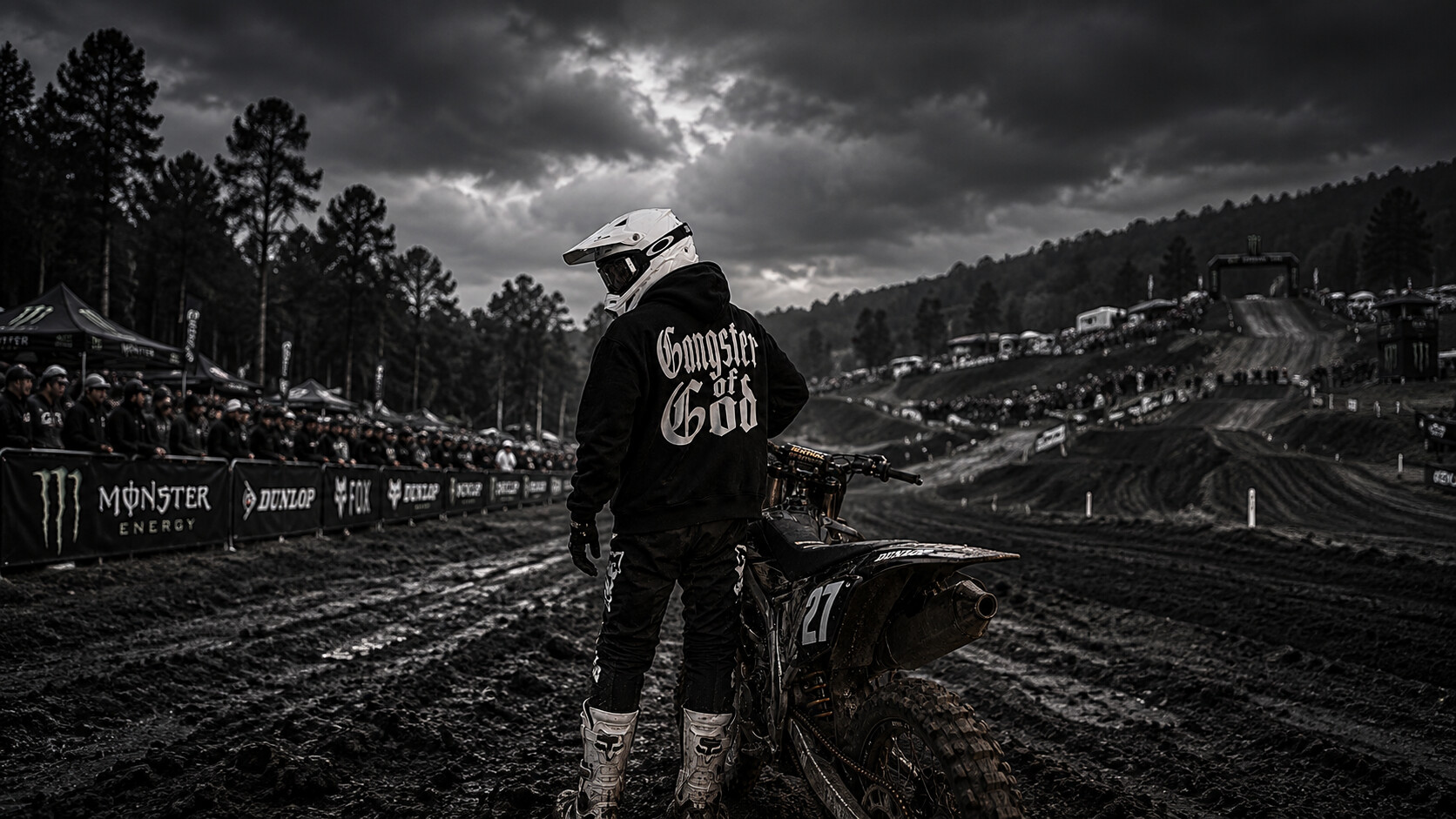 Helmeted rider wearing a solid-print Gangster of God hoodie at a dirt-bike track